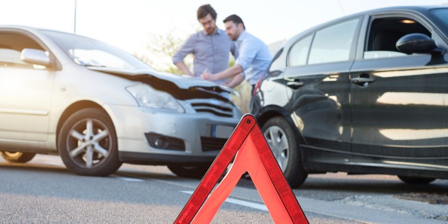 Two car accident, two men discussing and in front an orange triangle warning sign