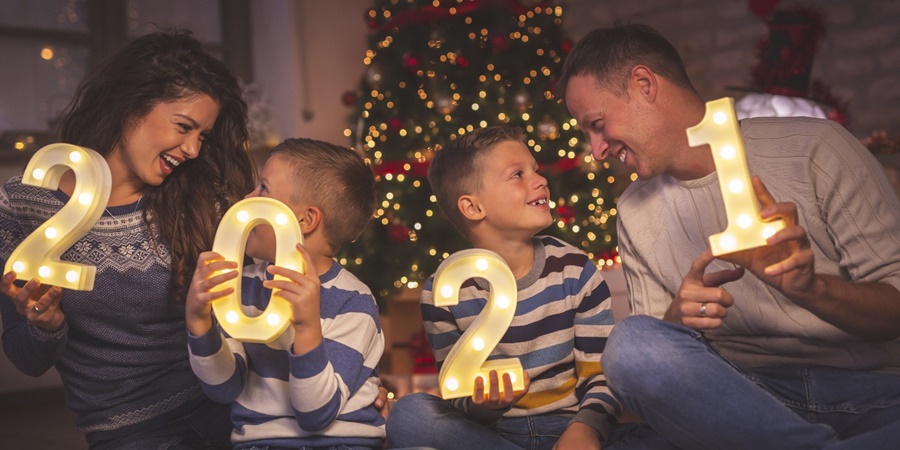 Family celebrating Christmas in front of the tree holding 2021 numbers single number each