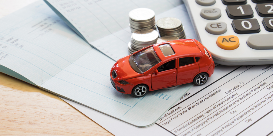 Red toy car, coins, calculator and Insurance policy on top of a table