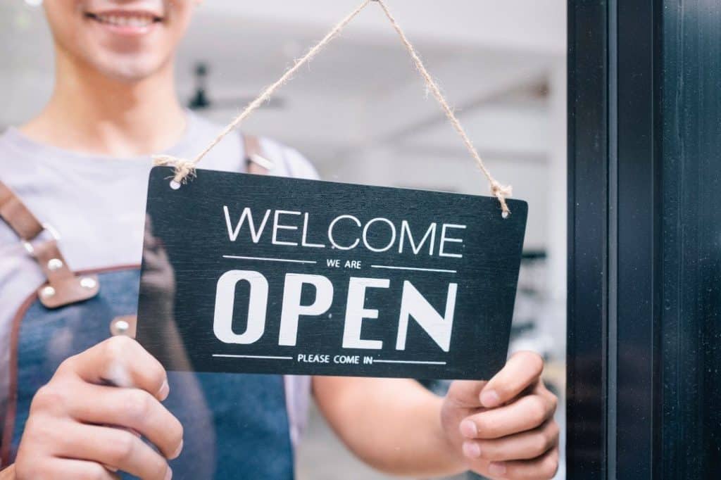 Business owner hanging the open sign on the door