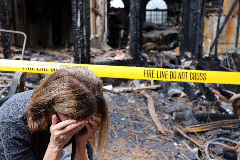 Woman crying outside her burned down home