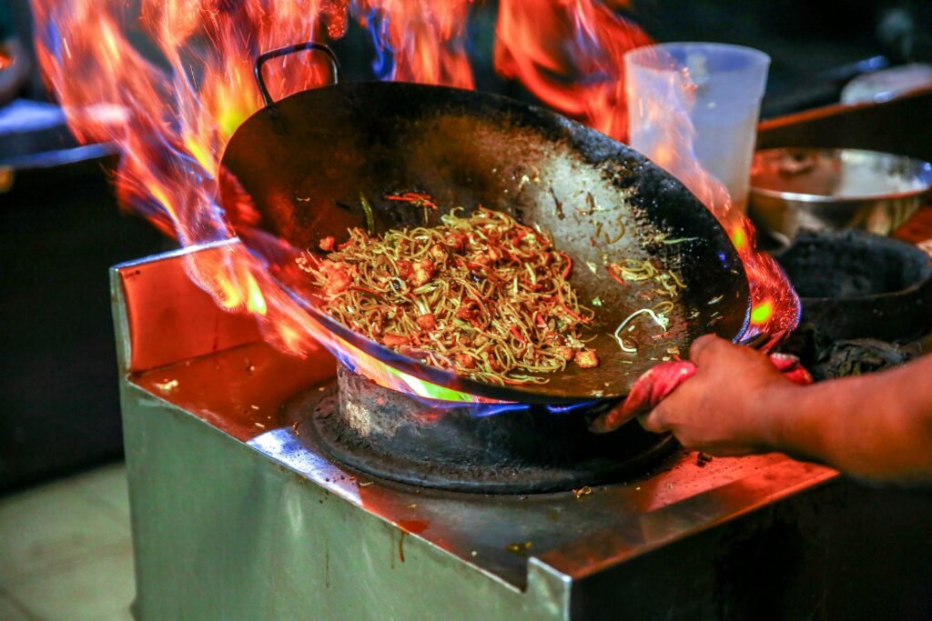 A restaurant worker wearing heat-resistant gloves in a kitchen setting.